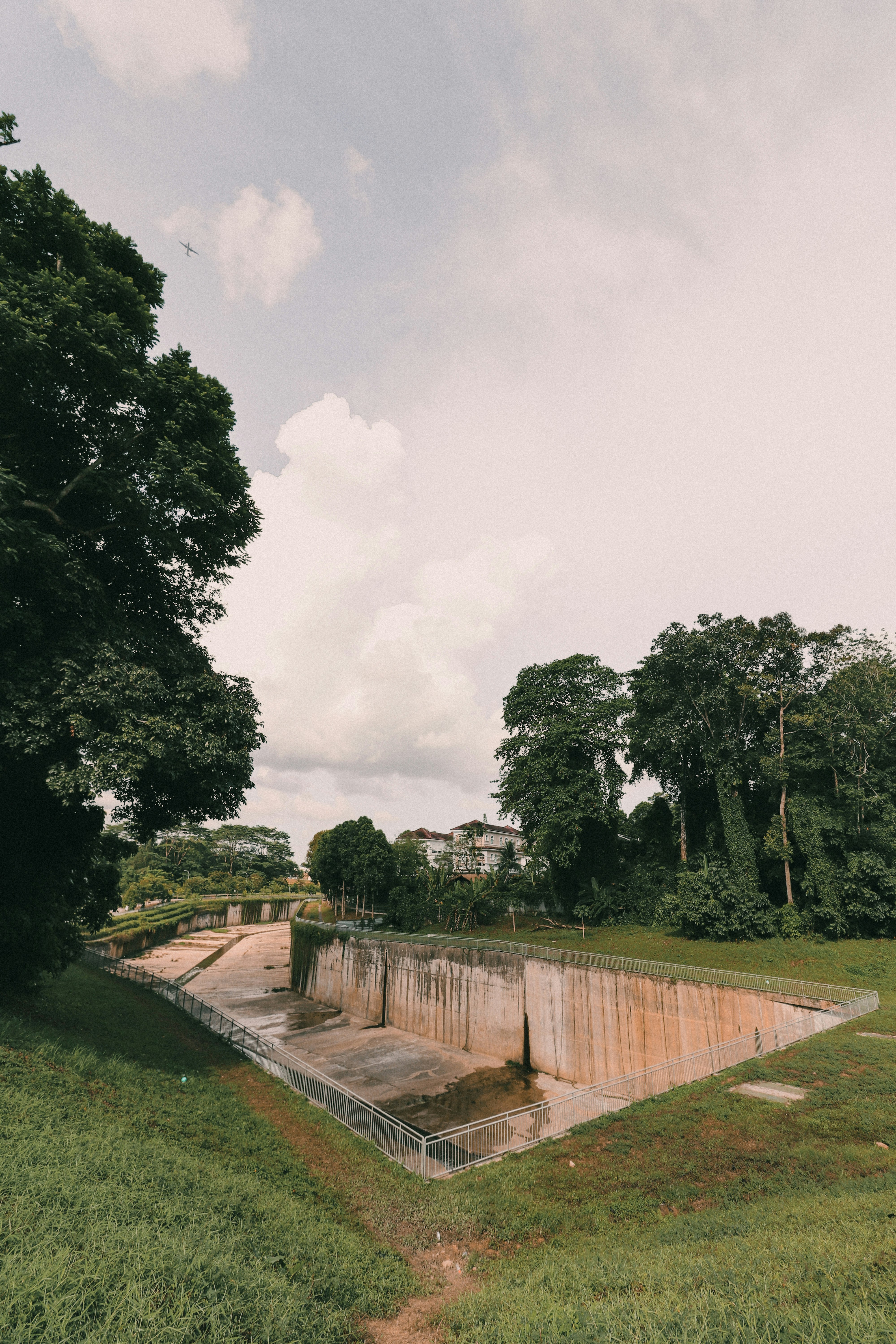 green trees near gray concrete pathway under white sky during daytime